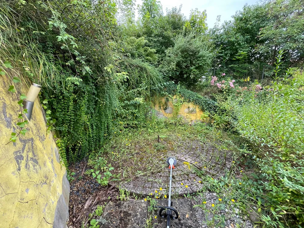 Zugewachsener runder Sitzplatz vor der Gartenarbeit