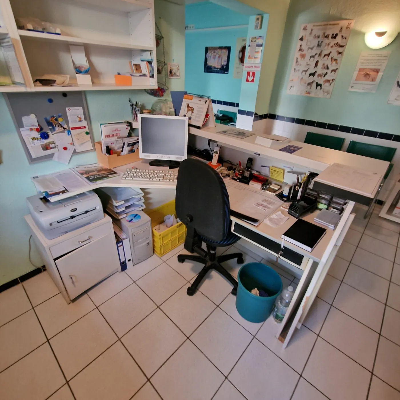 Empfangsbereich einer Praxis mit Schreibtisch, PC und Regalen vor der Räumung